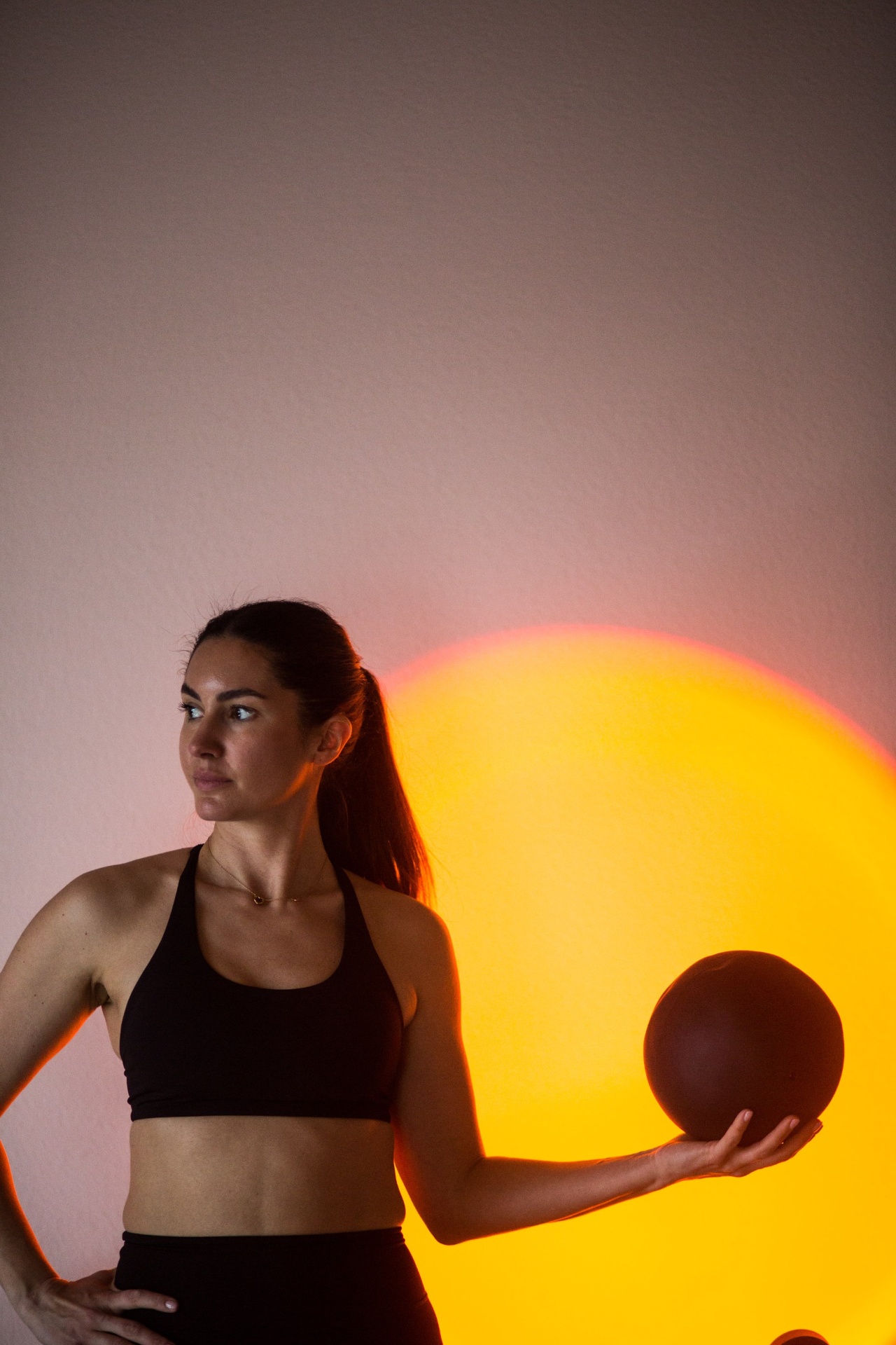Simona holding a Pilates ball in warm sunset light